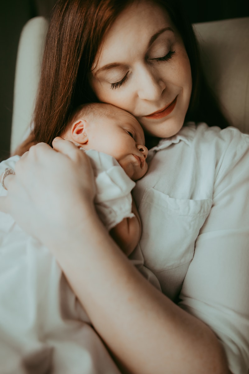a new mom quietly embracing her newborn baby in soft light winchester virginia newborn photographer