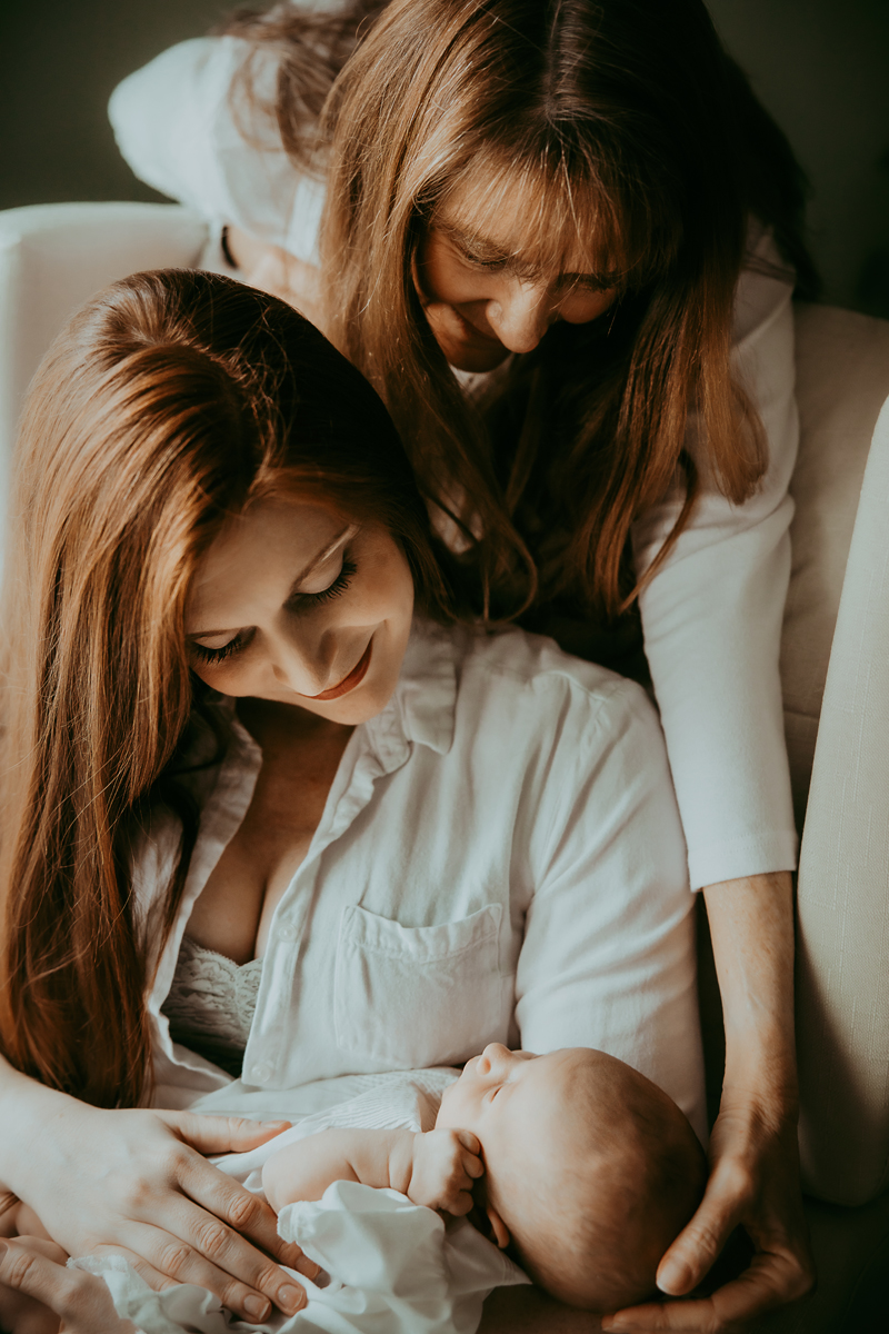A mom lovingly embracing her daughter and her new granddaughter captured by a Hagerstown Maryland Newborn photographer