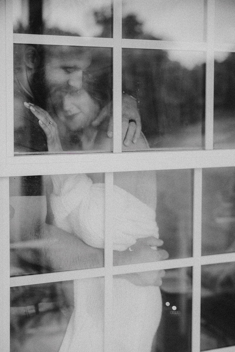 a couple in a loving embrace photographed through an exterior window captured by a Hagerstown Maryland couples photographer